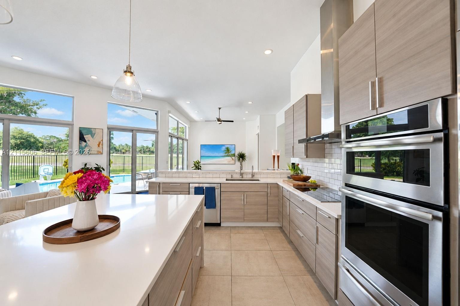 Kitchen featuring a large central island with a quartz countertop, wood-finish cabinetry, stainless steel double wall ovens, a white subway tile backs