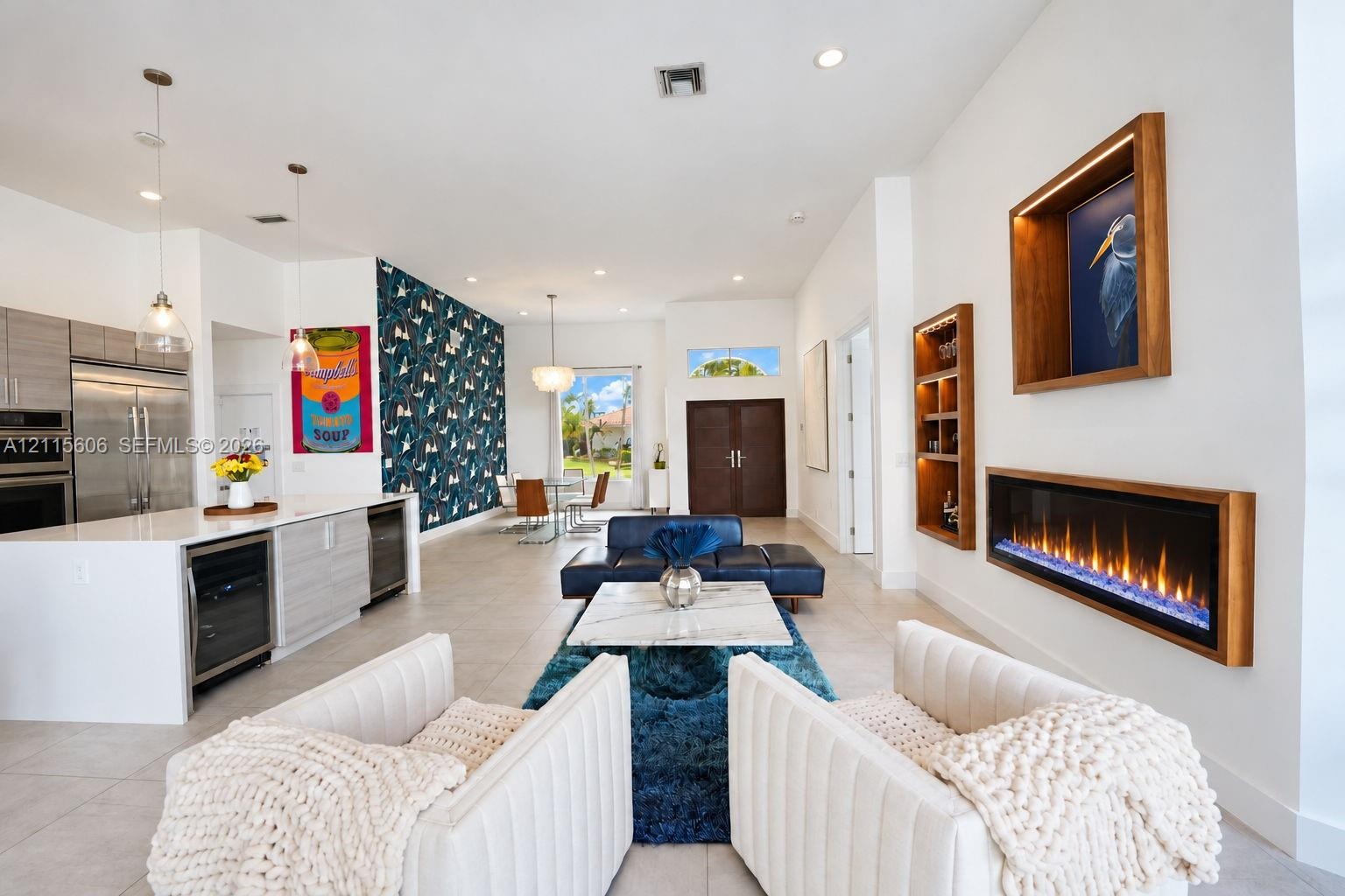 Open-concept interior featuring large-format tile flooring, a wall-mounted linear electric fireplace with wood trim, built-in recessed shelving, a cen