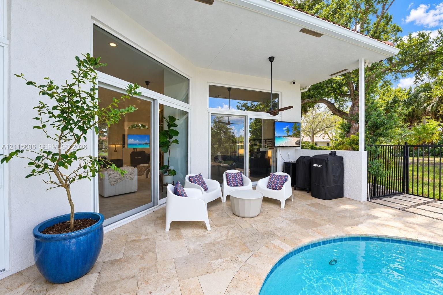 Covered patio featuring stone tile flooring, a swimming pool, multiple sliding glass door sets, and a ceiling-mounted fan