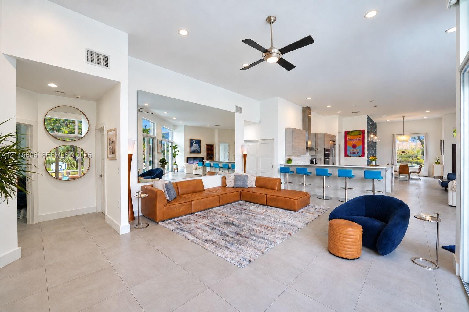 Open-concept interior featuring large-format tile flooring, recessed ceiling lighting, a contemporary ceiling fan, and a kitchen island with integrate