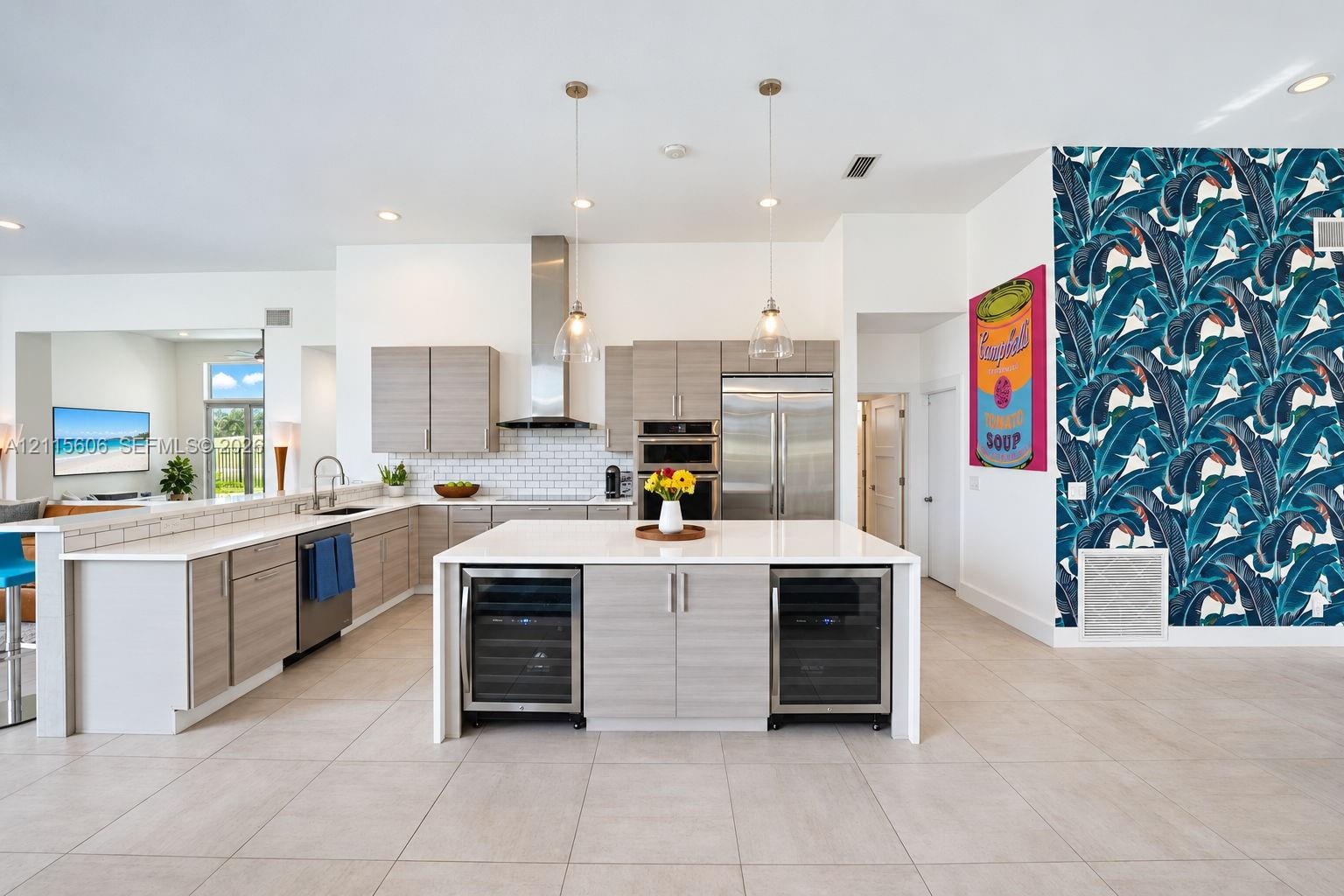 Kitchen featuring light-finish slab cabinetry, quartz countertops, stainless steel appliances, a central island with dual under-counter wine refrigera