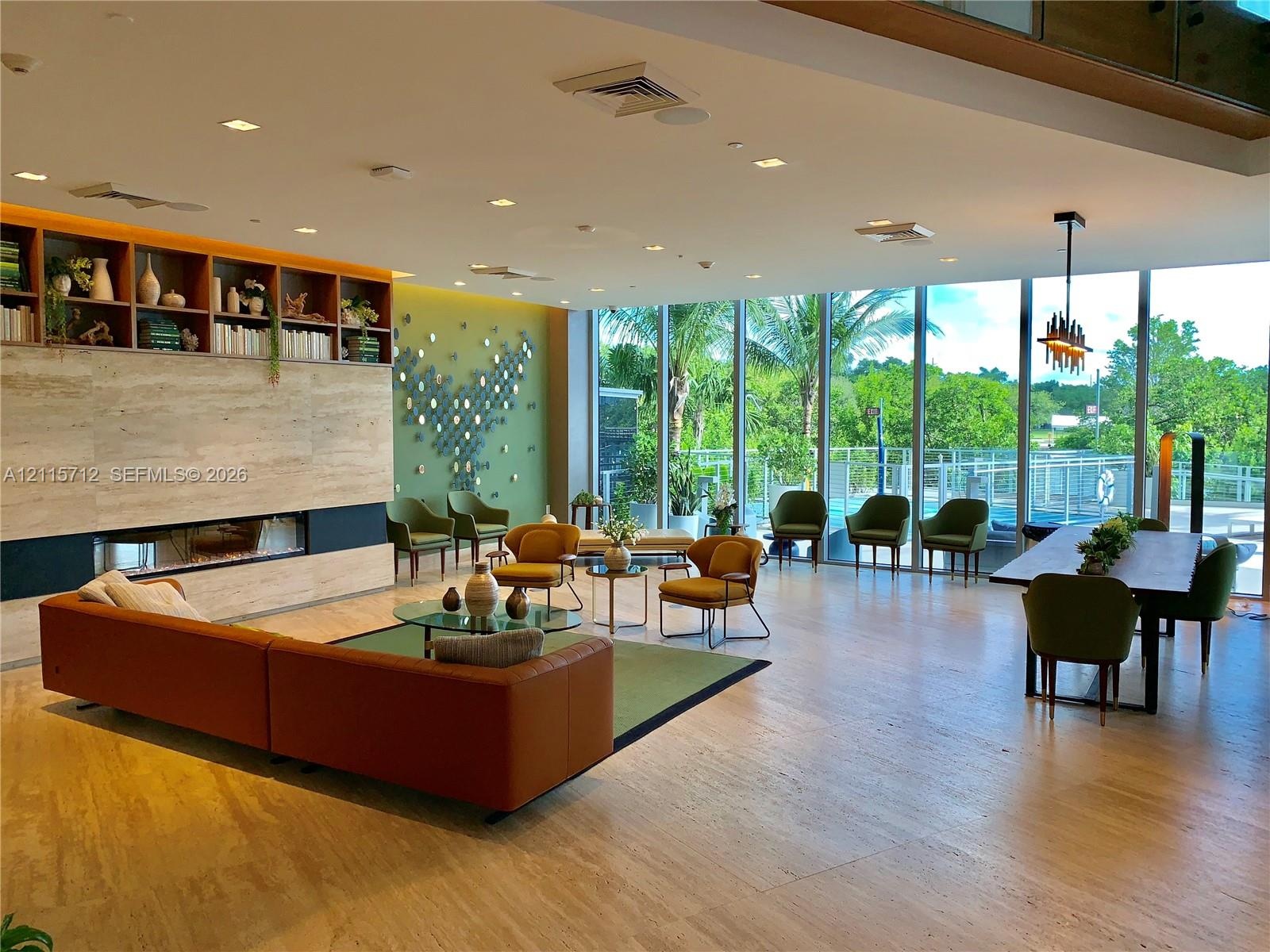 Open-concept interior featuring floor-to-ceiling glass walls, large-format stone-finish flooring, a linear built-in fireplace, and expansive built-in 