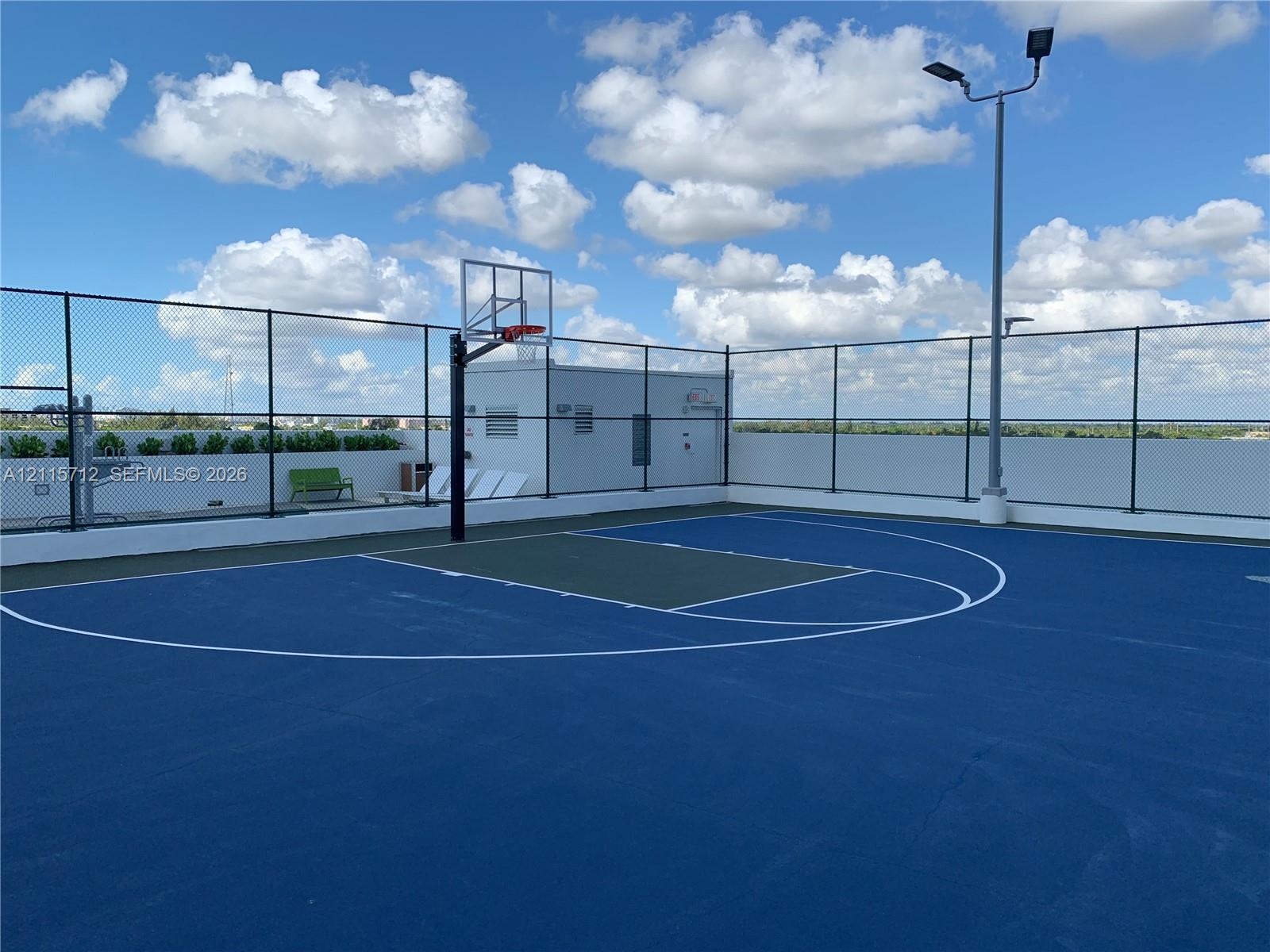 Rooftop basketball court featuring a high-performance surface, integrated lighting system, and full-perimeter chain-link fencing