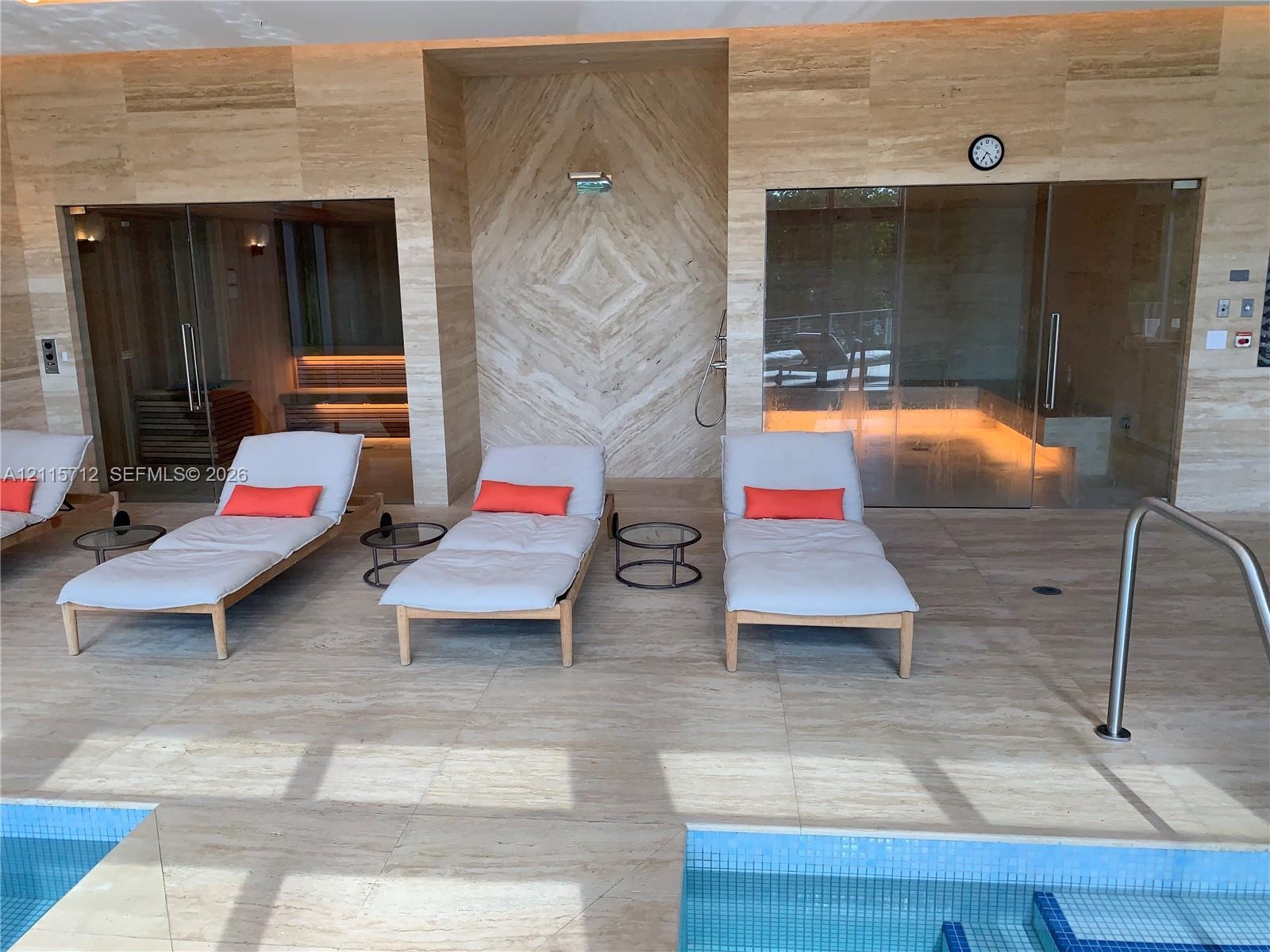 Spa area featuring full-height natural stone wall cladding, floor-to-ceiling glass-enclosed sauna, steam room, and built-in tiled plunge pool with int