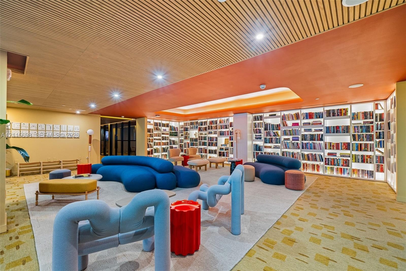 Custom floor-to-ceiling built-in library shelving with integrated LED illumination, wood-slat ceiling detailing, recessed lighting, and patterned carp