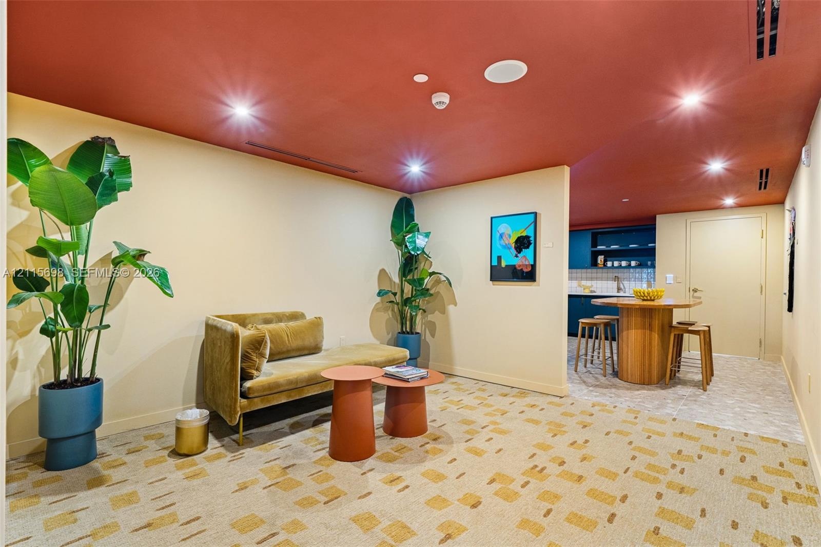 Interior space featuring a recessed ceiling with integrated lighting, patterned carpeting, and a kitchen area with built-in dark cabinetry and shelvin