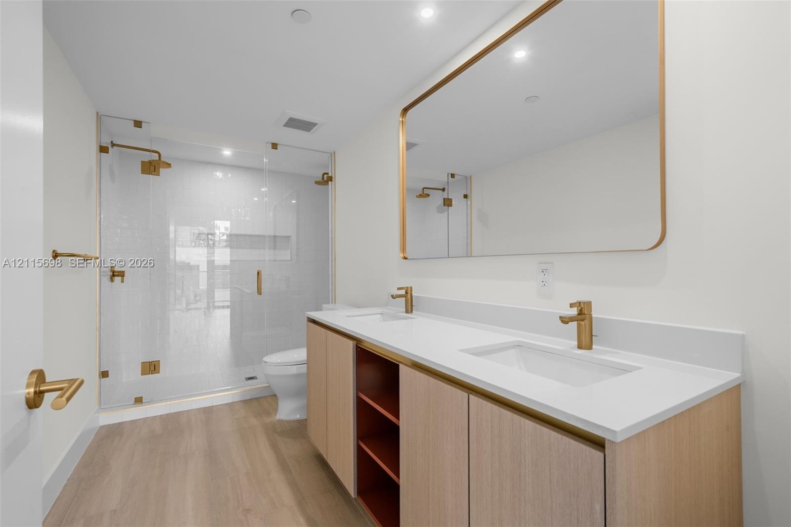 Master bathroom Dual-sink vanity with light wood cabinetry, white countertop, and gold-finish fixtures, complemented by a glass-enclosed walk-in showe