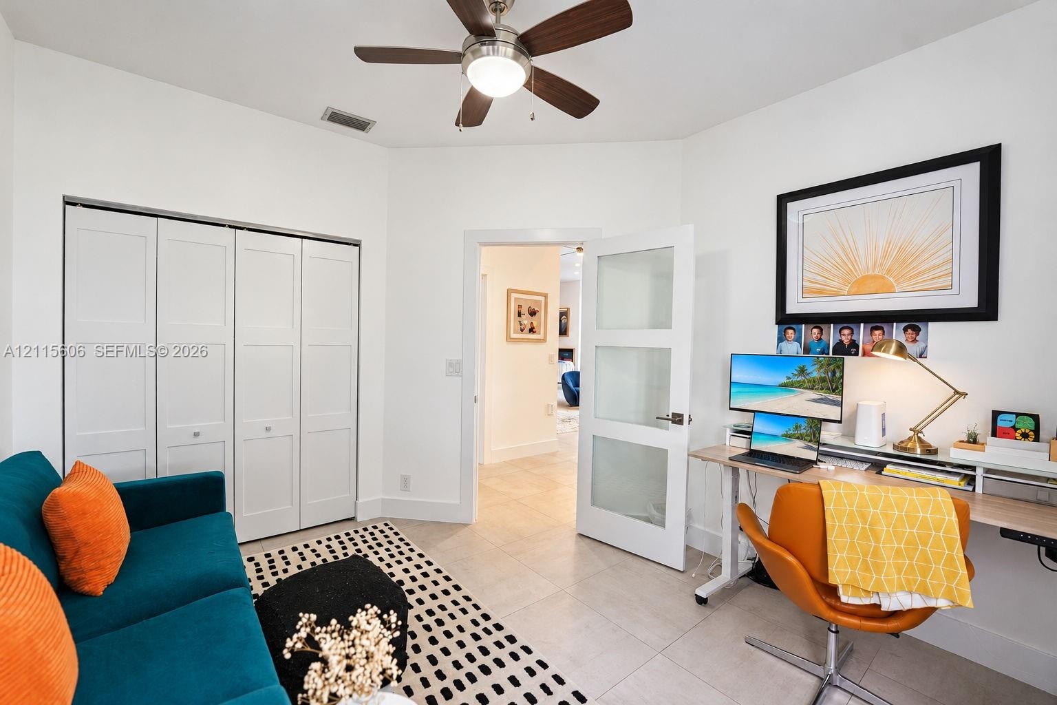 Interior room featuring neutral tile flooring, a multi-panel closet with white doors, a ceiling fan with integrated lighting, and a white interior doo