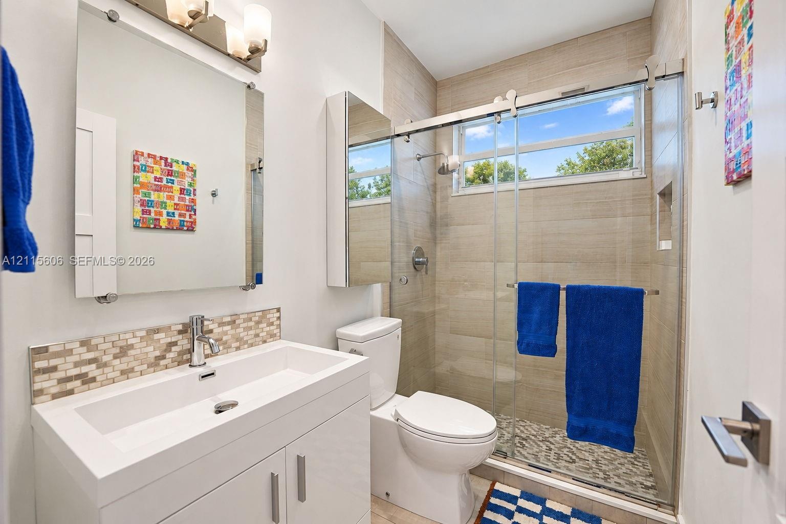 Modern vanity with rectangular sink and mosaic tile backsplash, frameless glass shower enclosure, horizontal tile shower surround, and integrated wall