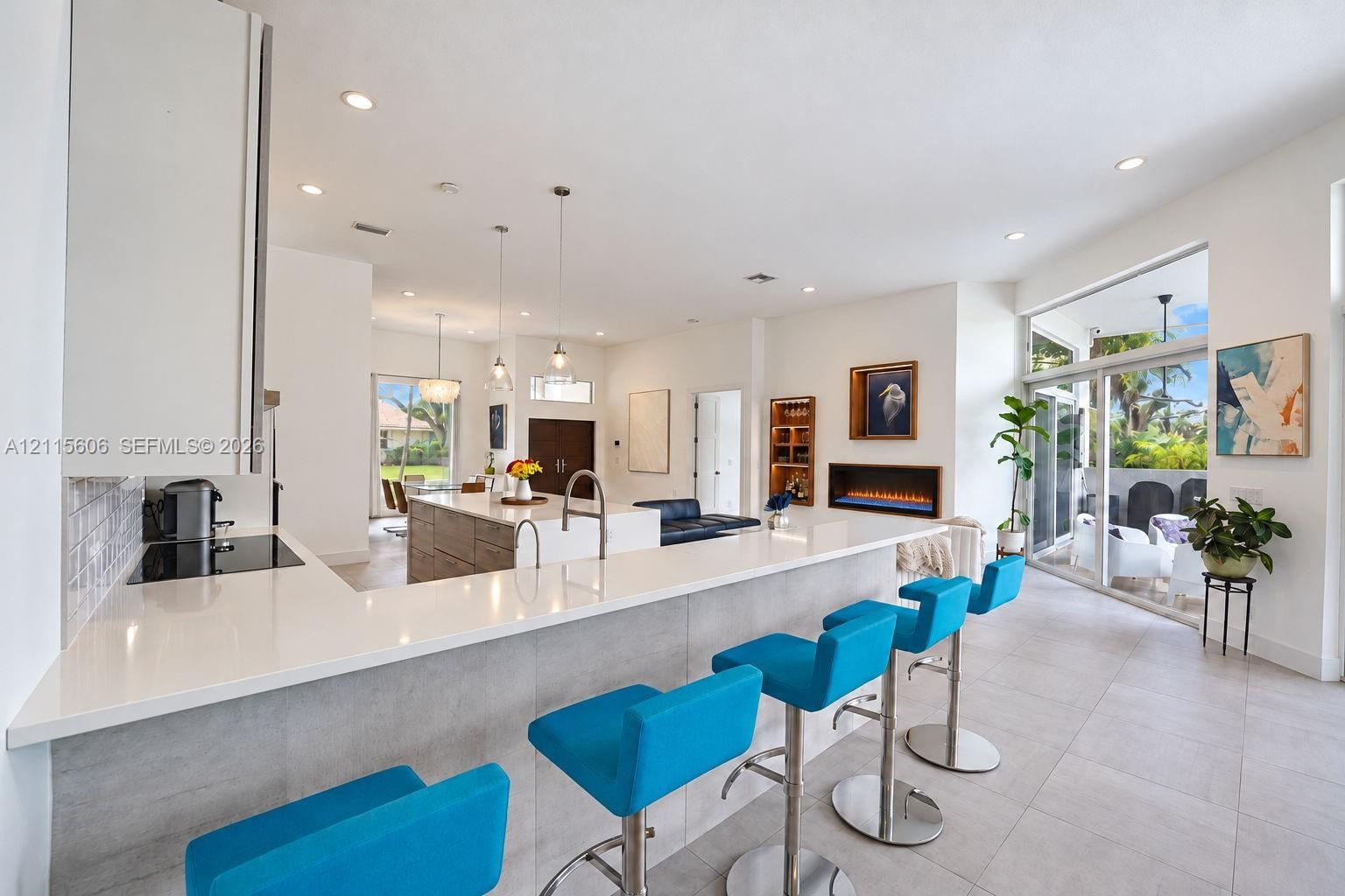 Kitchen featuring an extended quartz countertop island, built-in cabinetry, flush-mounted lighting, and a linear wall-recessed fireplace