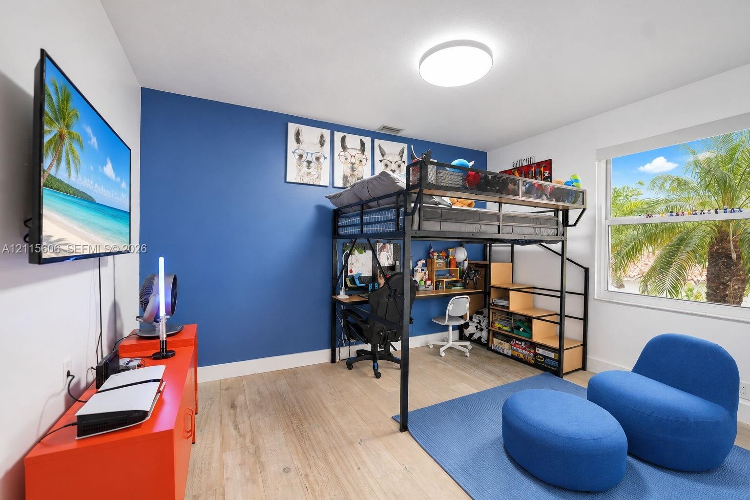 Room featuring wood-finish flooring, a vibrant blue accent wall, and a large horizontal window
