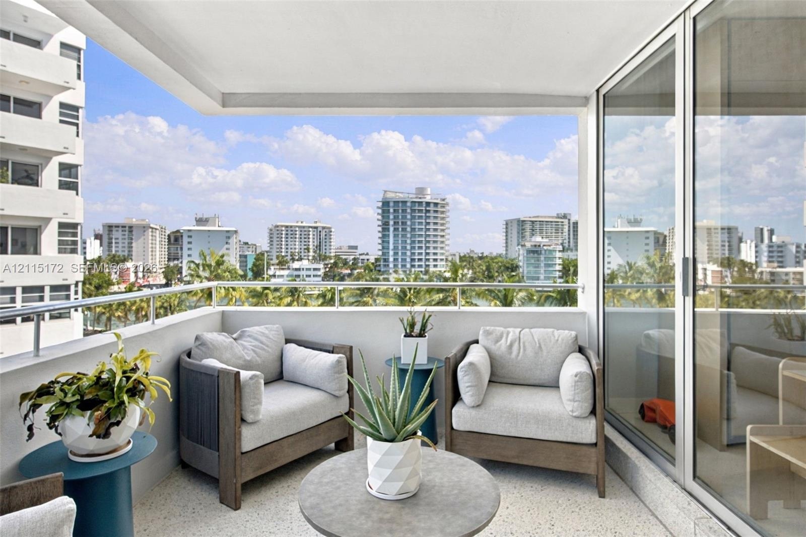 Covered balcony featuring a metal railing and terrazzo flooring, offering an expansive outlook of the surrounding cityscape