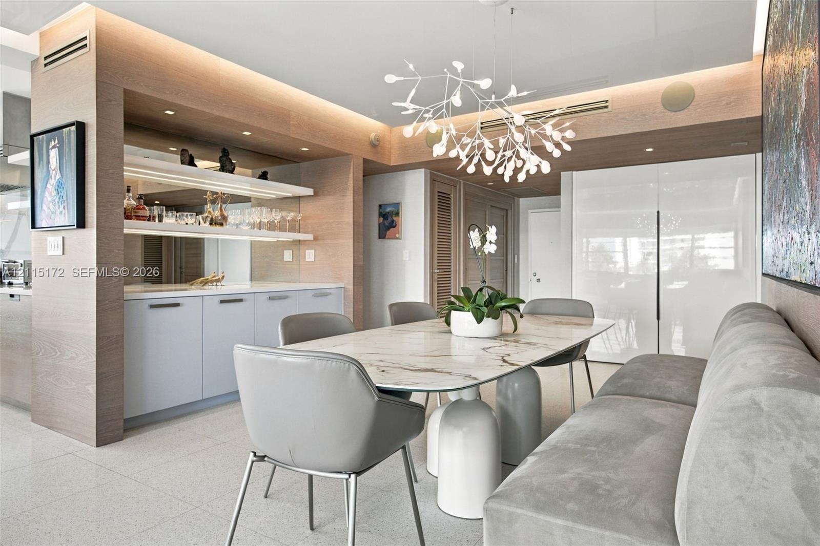 Custom built-in cabinetry with integrated lighting and stone surfacing, complemented by light-toned wood-finish wall paneling, high-gloss cabinetry, a