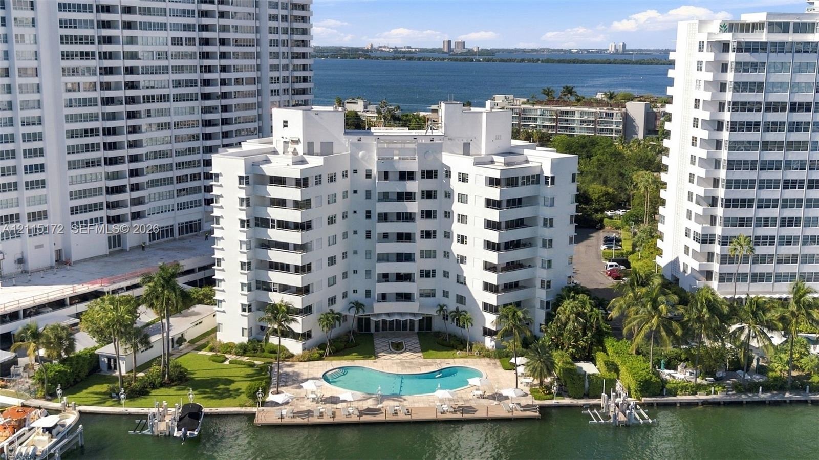 Multi-story residential building featuring private waterfront access, an outdoor swimming pool, a concrete pool deck, and manicured landscaping