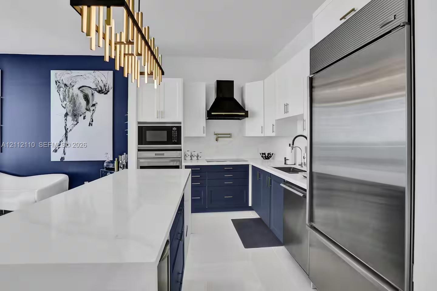 Kitchen featuring a large central island with quartz countertops, two-tone cabinetry, professional-grade stainless steel appliances, a wall-mounted po