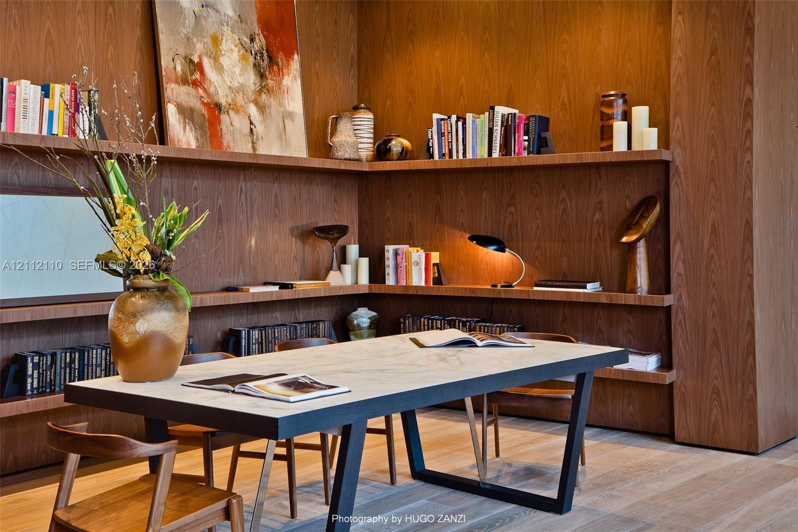 Floor-to-ceiling wood paneling with integrated multi-level shelving, wood-finish flooring, and a stone-topped table with a matte black metal frame