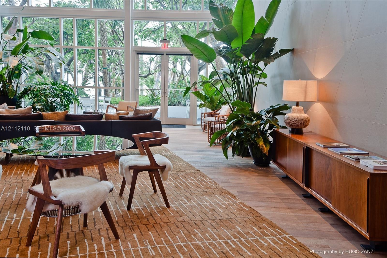 Floor-to-ceiling windows, glass-paned double doors, wood-finish flooring, and recessed wall sconces