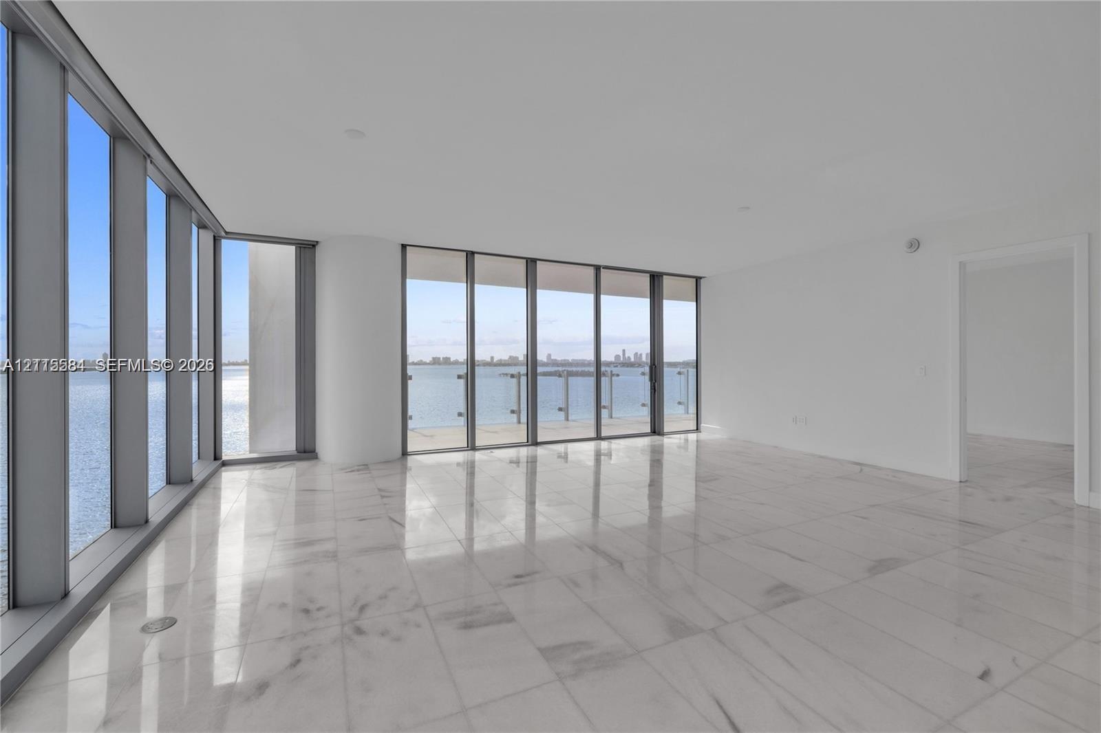 Floor-to-ceiling windows, polished stone flooring, and metal-framed exterior railing