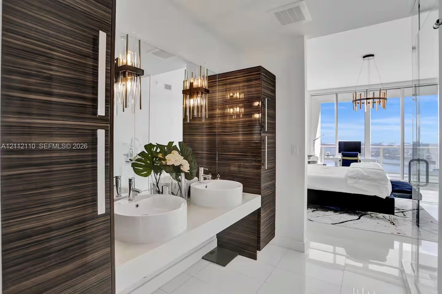 Floating vanity with dual vessel sinks, high-gloss horizontal wood-grain cabinetry, polished stone countertop, and statement vertical pendant lighting