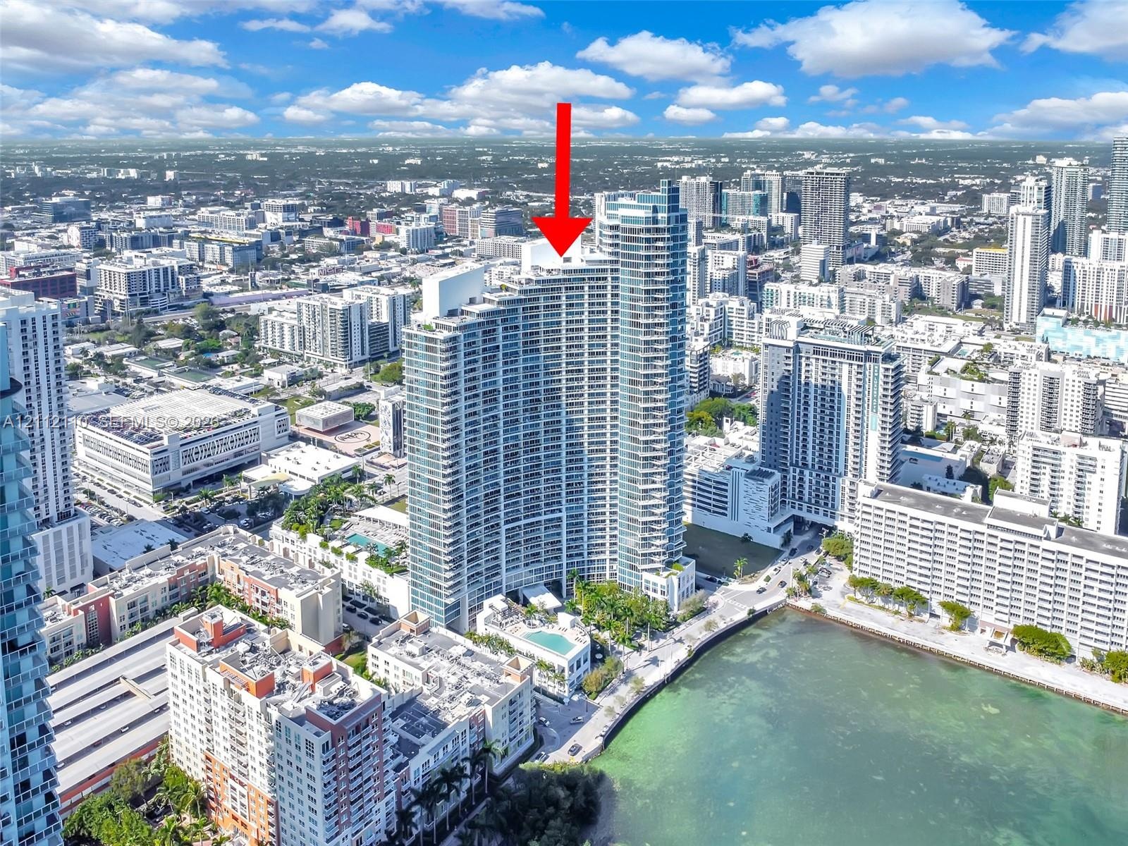 High-rise condominium building featuring glass-paneled exterior, private balcony, and on-site pool