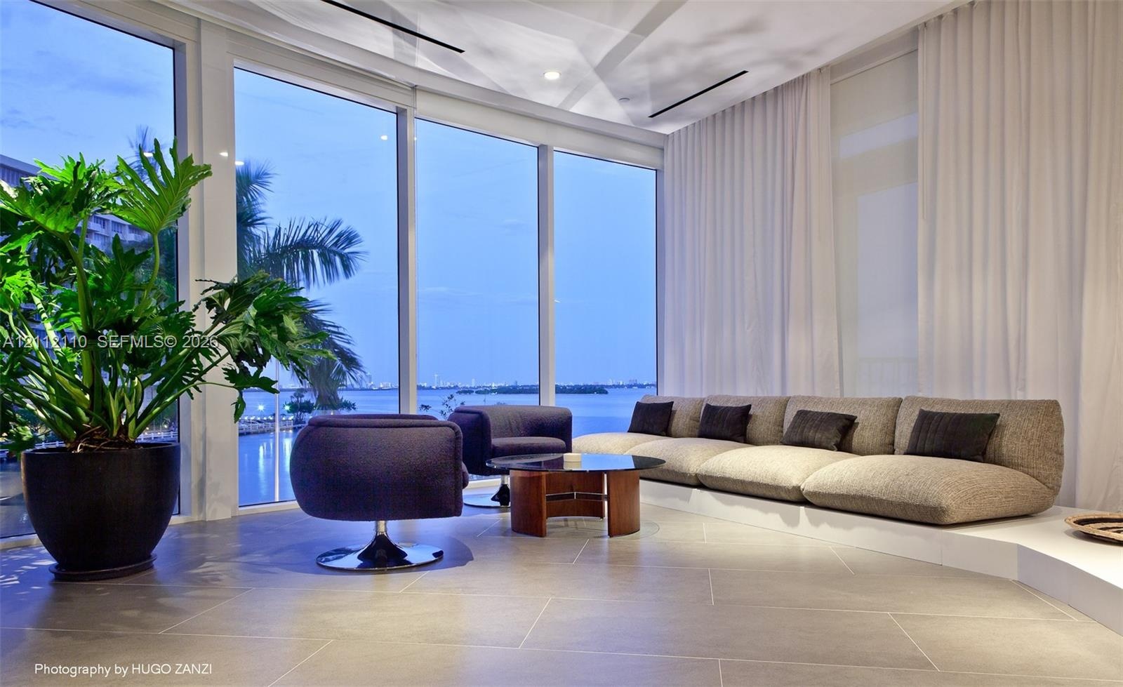 Floor-to-ceiling windows featuring expansive glass panels, large-format tile flooring, recessed ceiling lighting, and a tiered platform structure