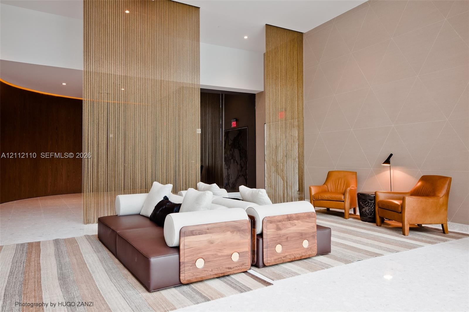Metallic chain-link room dividers, recessed ceiling lighting, curved wood-paneled walls, and geometric patterned wall texture