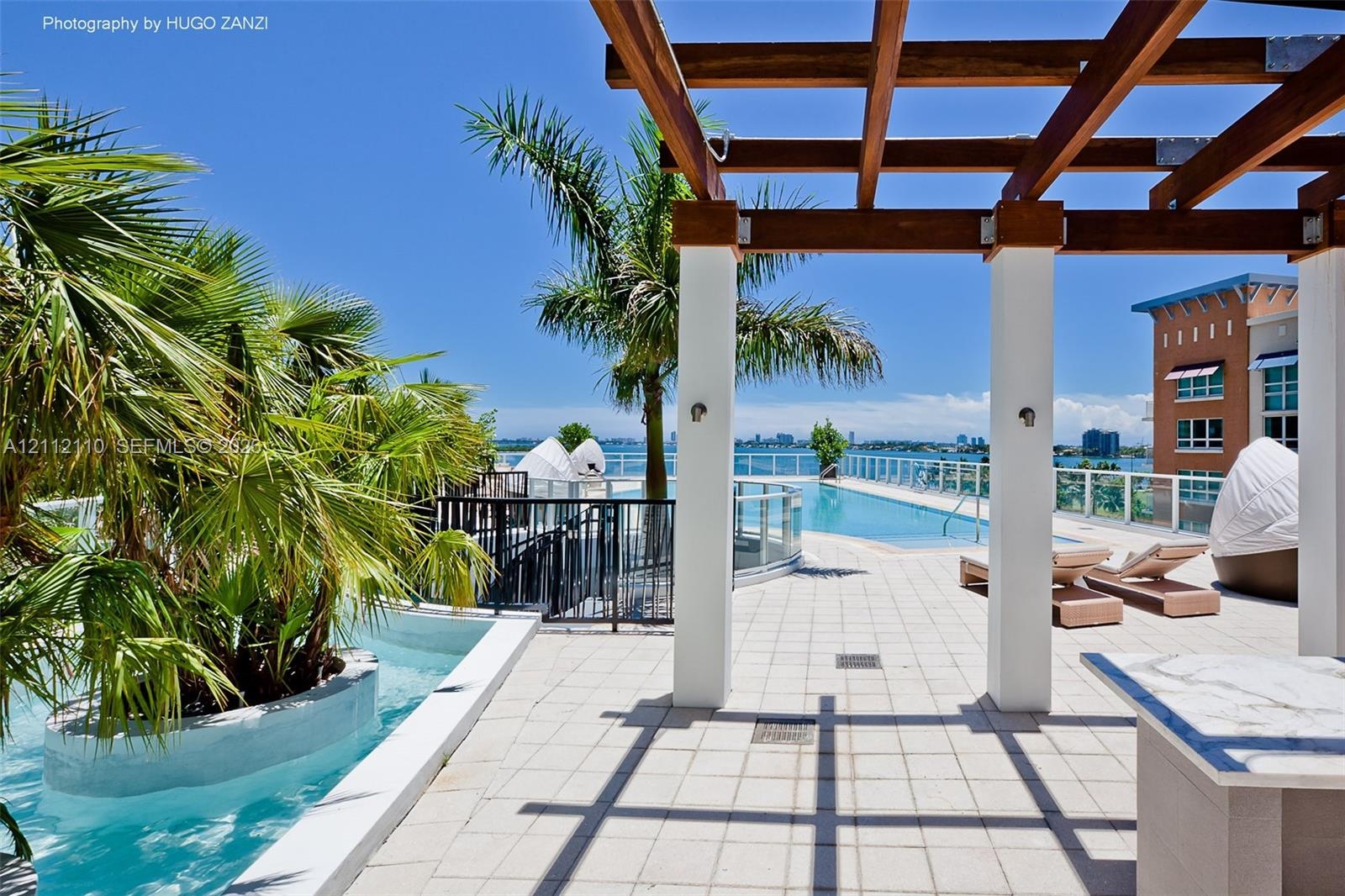 Rooftop terrace featuring a wooden pergola, swimming pool with glass railing, stone-finish tiling, and built-in stone-top counter