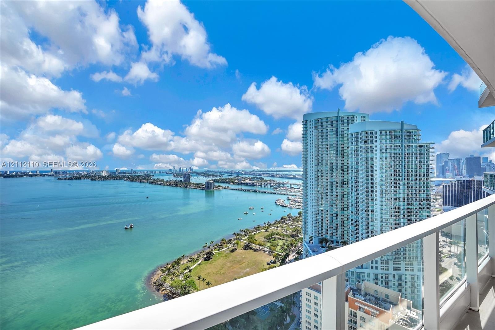 Private balcony featuring a glass panel railing and panoramic water and skyline scenery