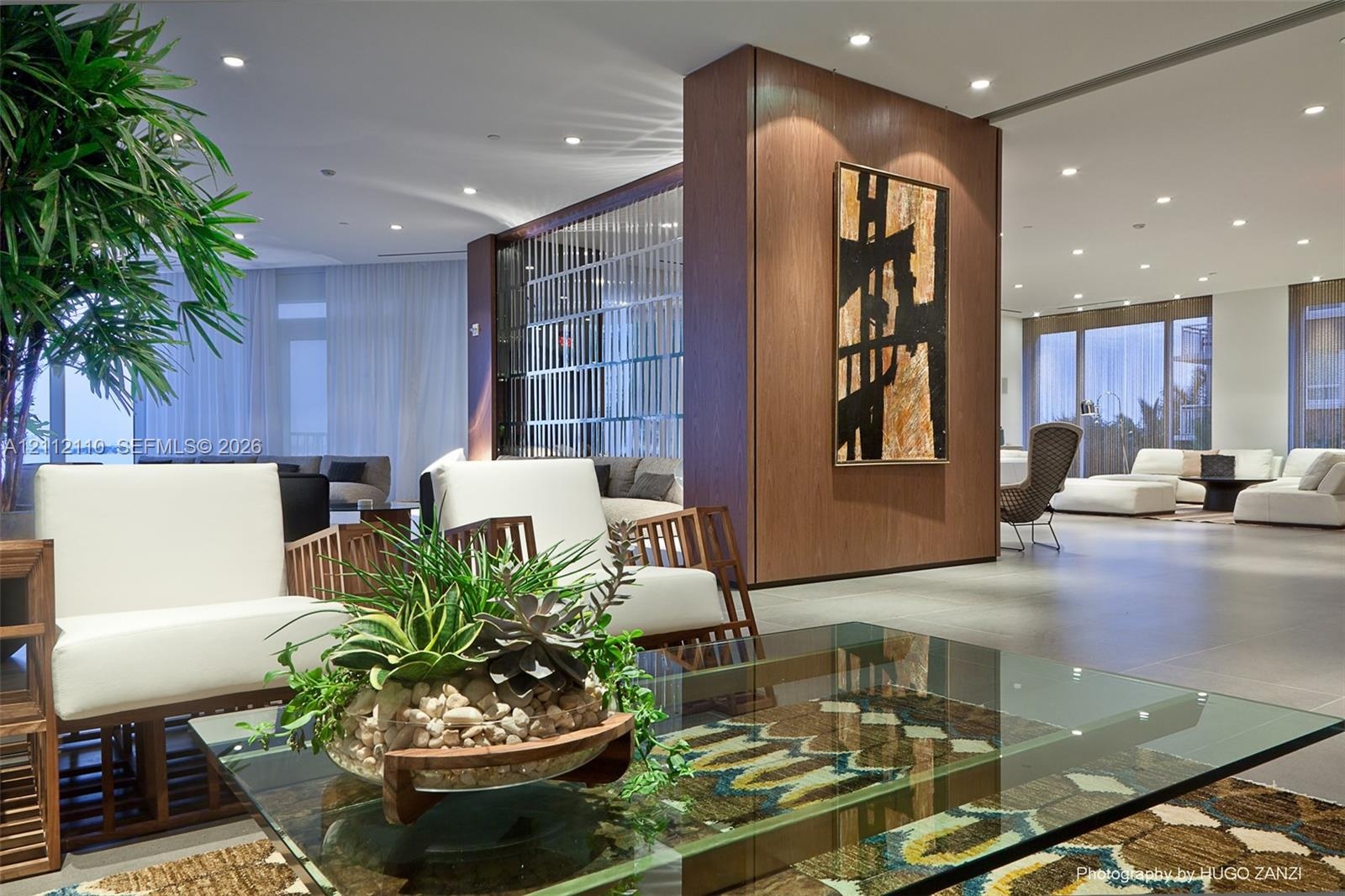 Wood-paneled structural column, polished stone flooring, recessed ceiling lighting, and decorative metal room partition