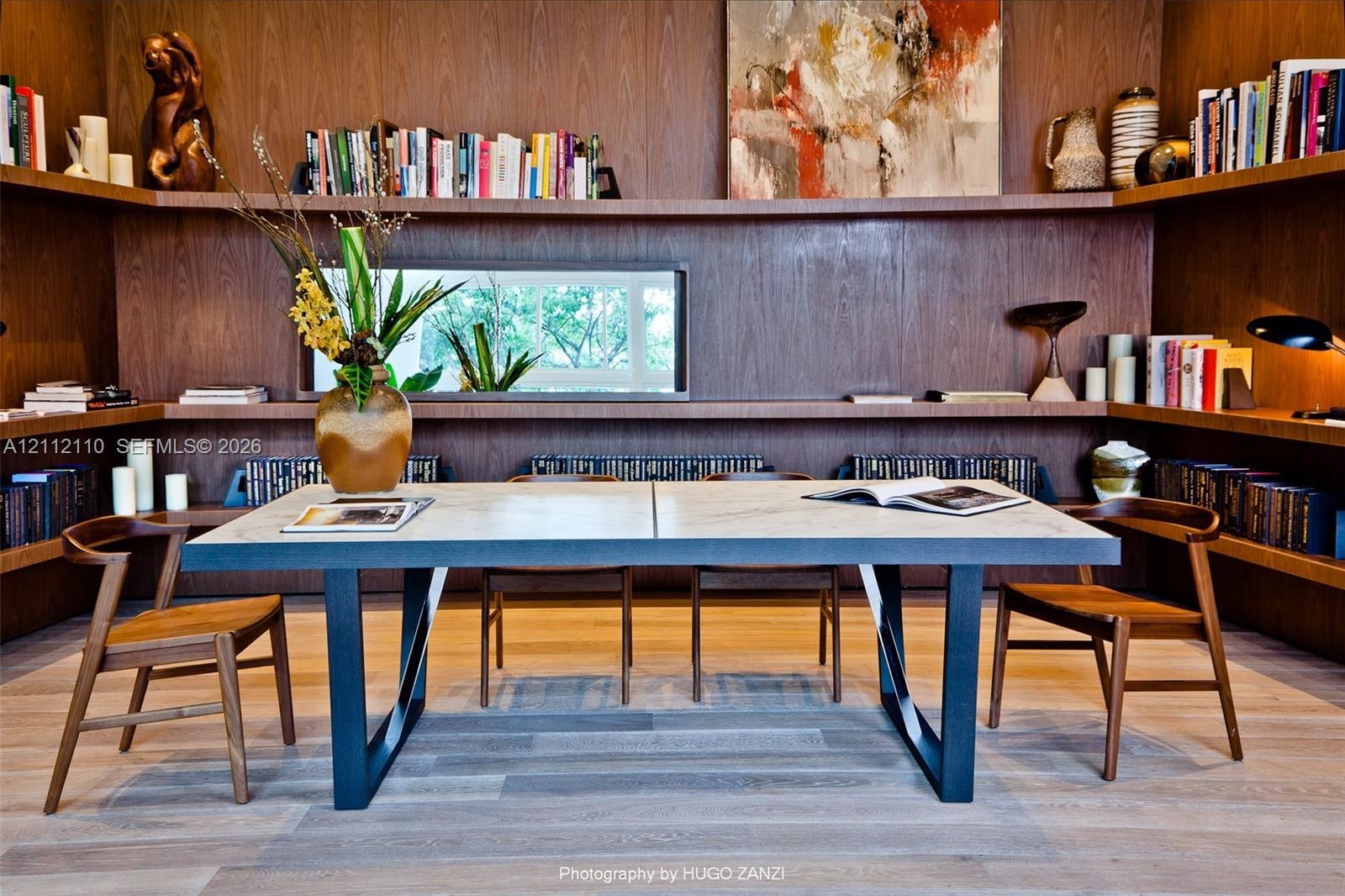 Custom wood-paneled walls featuring floor-to-ceiling built-in shelving, horizontal clerestory window, and wide-plank wood-finish flooring