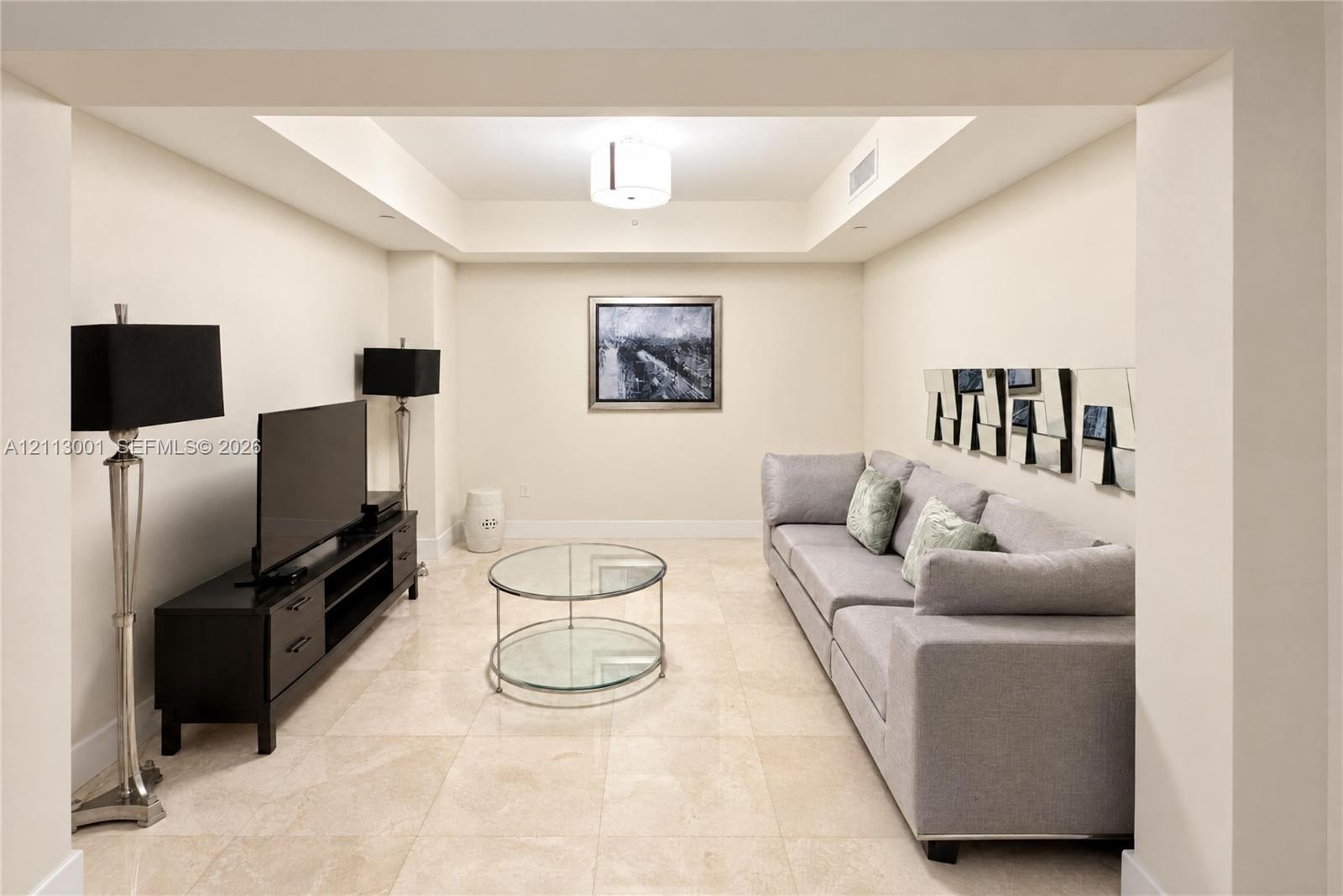 Neutral-toned room featuring a coffered ceiling, recessed lighting, and large-format tile flooring