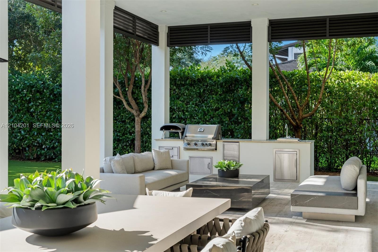Covered outdoor patio featuring an integrated kitchen with a stainless steel built-in grill, stone-finish countertops, and under-counter storage, fram
