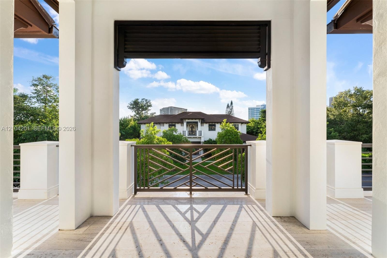 Covered terrace featuring stone flooring, substantial square pillars, and decorative geometric metal railing