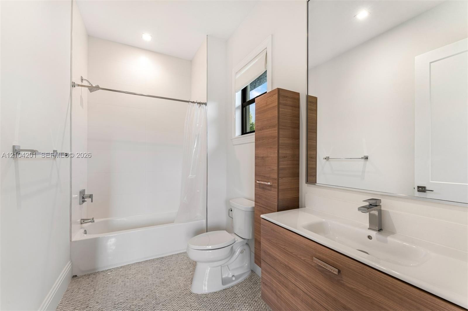 Bathroom featuring a wall-mounted wood-finish vanity with an integrated sink, floor-to-ceiling cabinetry, a full-height vanity mirror, and a tub-showe