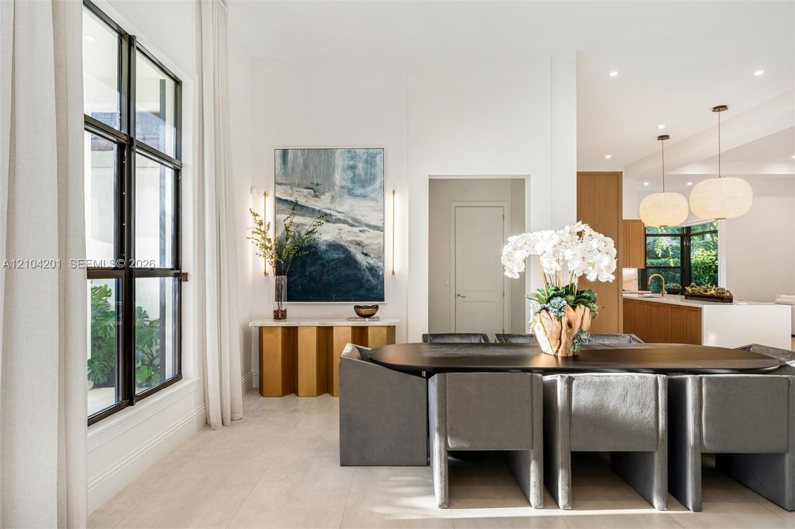 Large-format windows with black metal frames, recessed lighting, and dual textured pendant fixtures