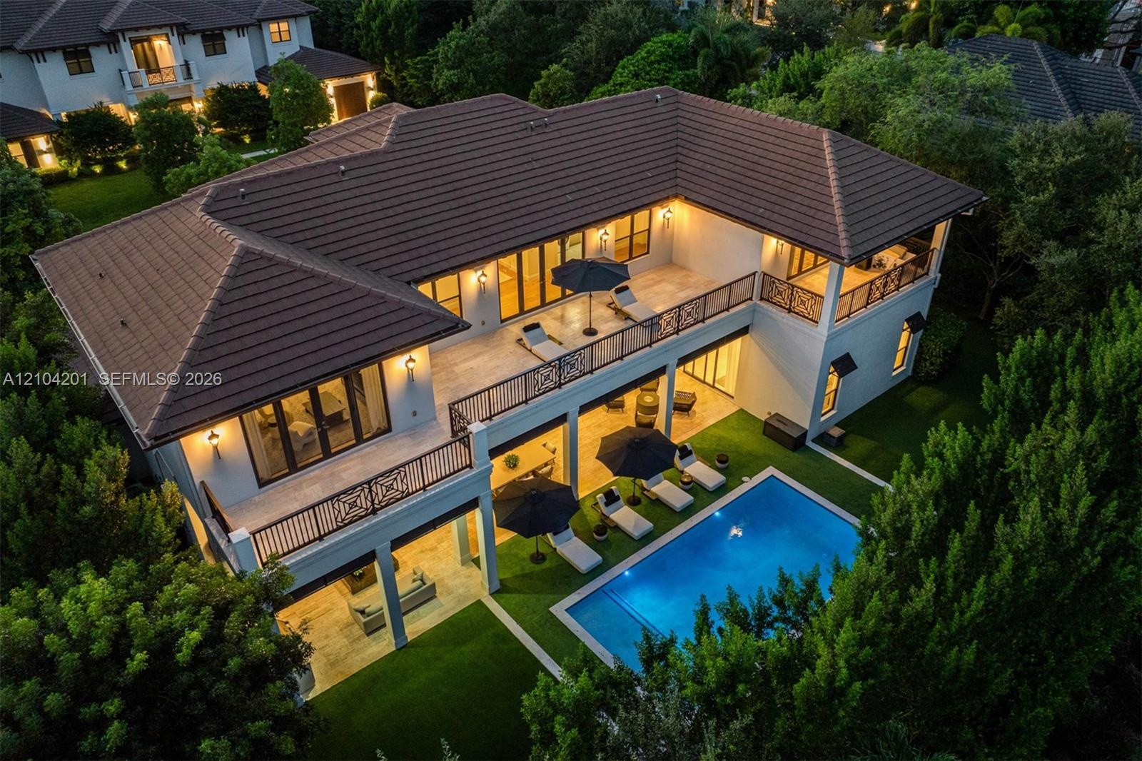 Two-story exterior featuring a tile roof, an expansive upper-level balcony with decorative railings, a lower-level covered patio, and a swimming pool 