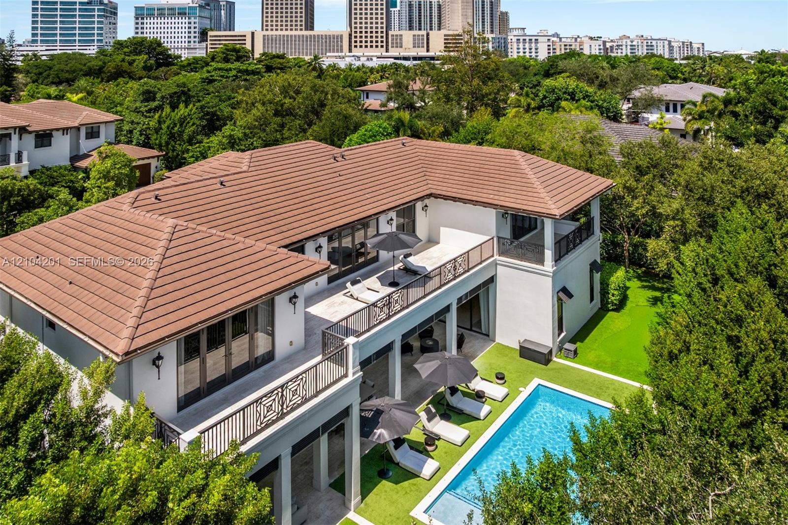Two-story exterior featuring a tile roof, dual-level balconies with decorative metal railings, ground-level covered patio, and rectangular swimming po