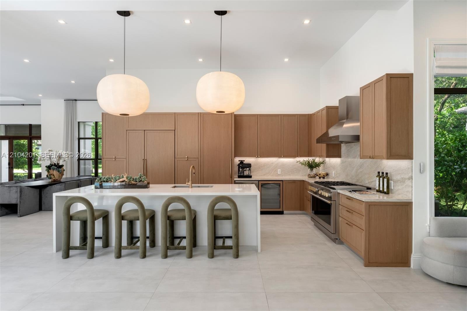 Kitchen featuring wood-finish cabinetry, a waterfall-edge island with a metallic faucet, stone-patterned backsplash, stainless steel professional-styl