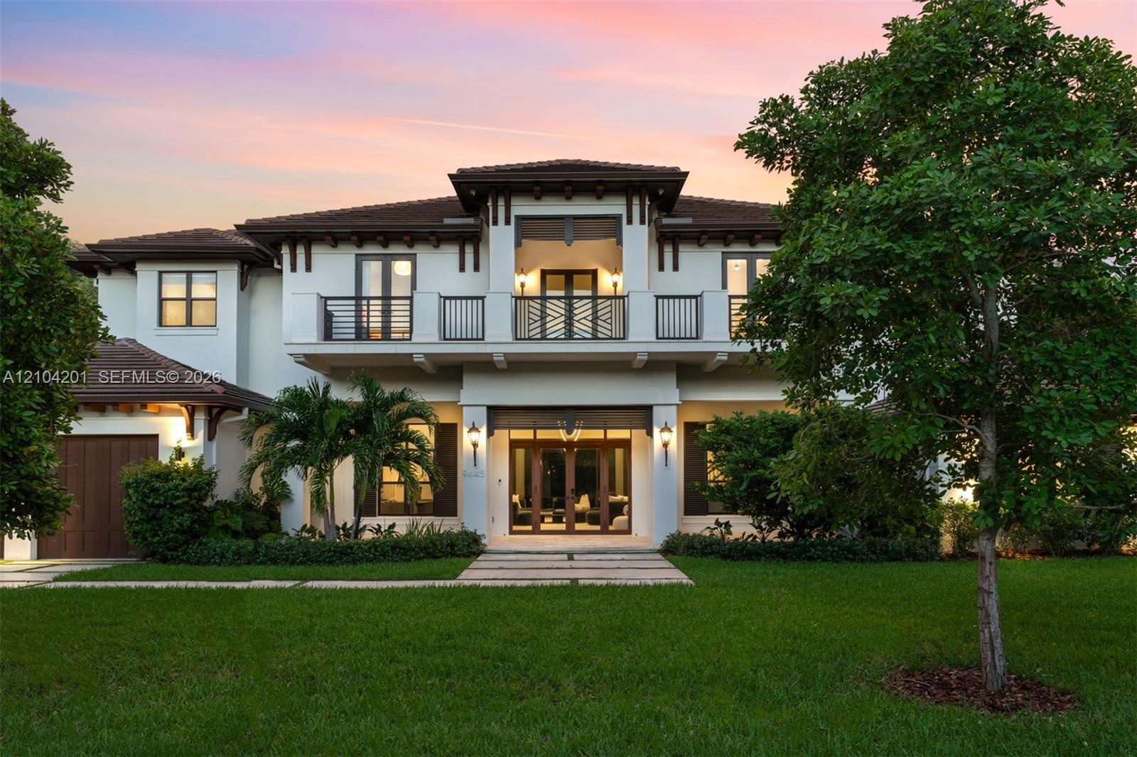 Two-story exterior featuring a tile roof, stucco finish, gated second-story balcony with metal railings, and a multi-pane glass entry door