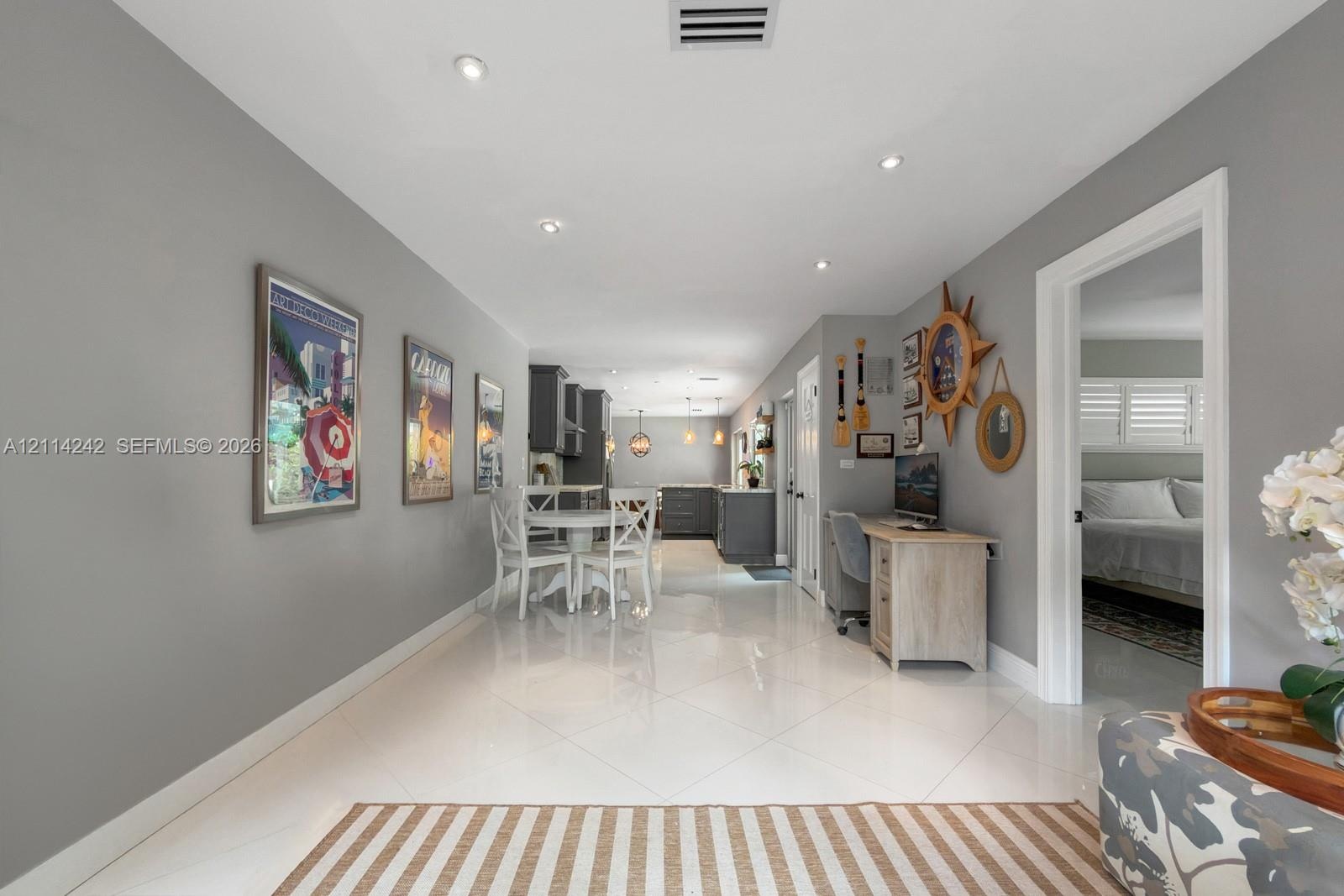 Neutral-toned interior featuring large-format porcelain tile flooring, recessed ceiling lighting, and solid-core interior doors