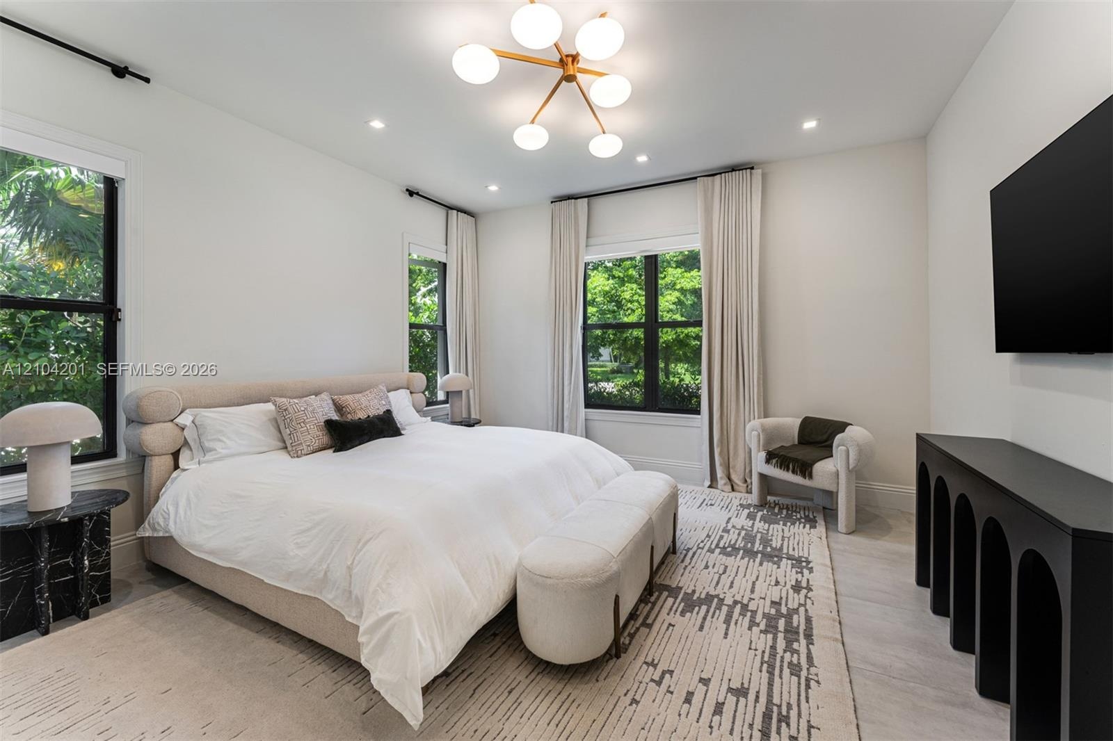 Spacious room featuring neutral wall tones, recessed lighting, a modern multi-globe chandelier, multi-pane windows with dark frames, and light wood-fi