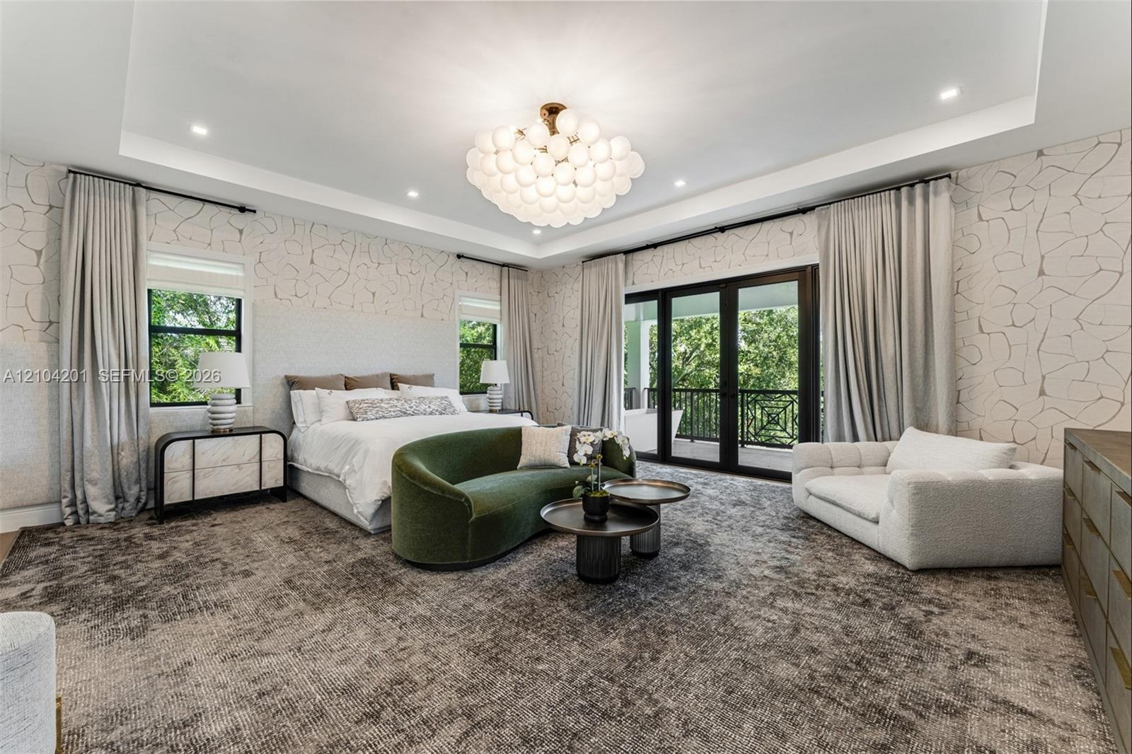 Tray ceiling featuring a globe-style multi-light fixture, patterned wall treatment, and black-framed multi-panel sliding glass doors opening to a balc