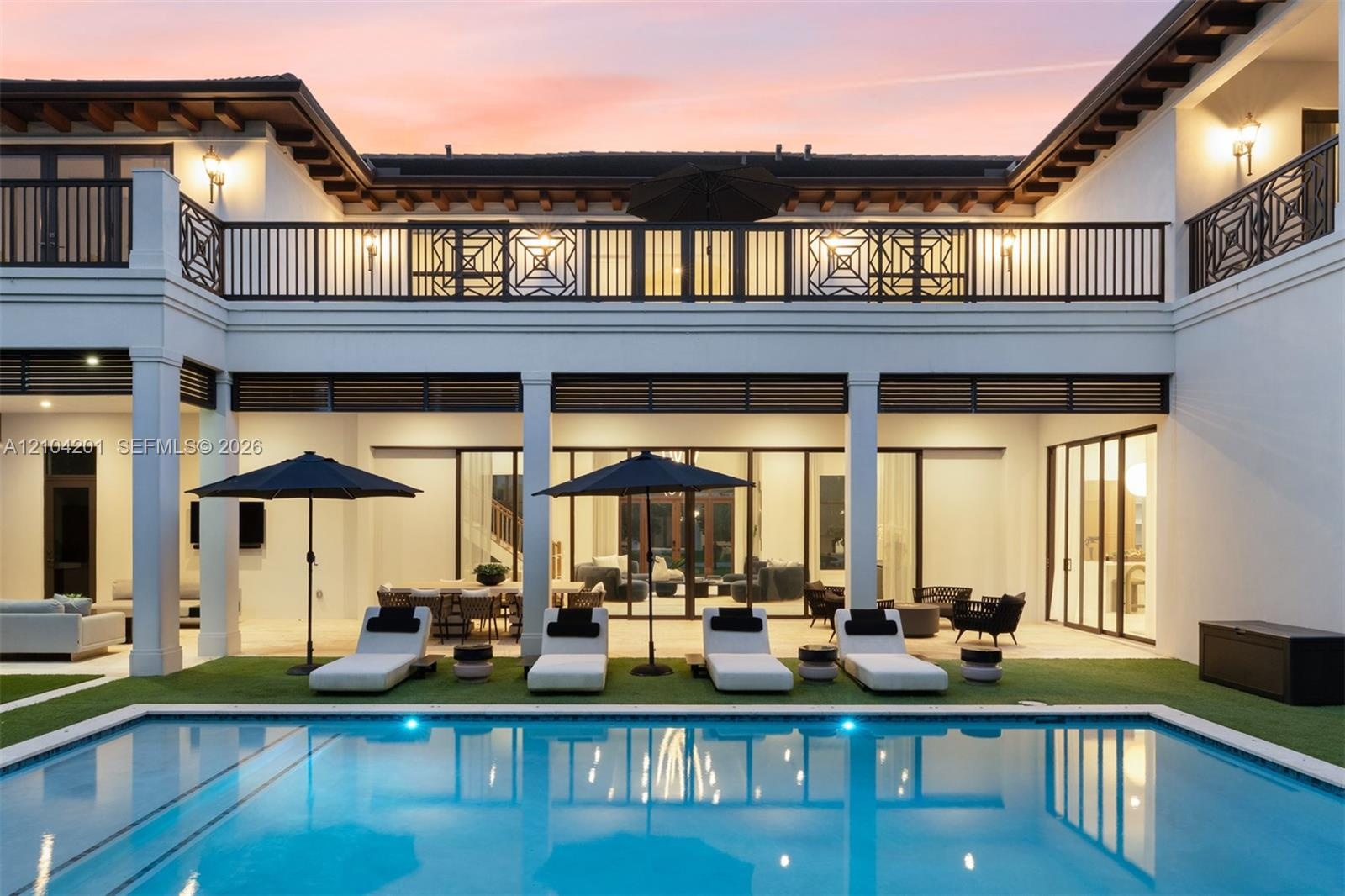 Rear exterior featuring a covered patio, rectangular swimming pool, second-story balcony with metal railing, and exposed ceiling beams