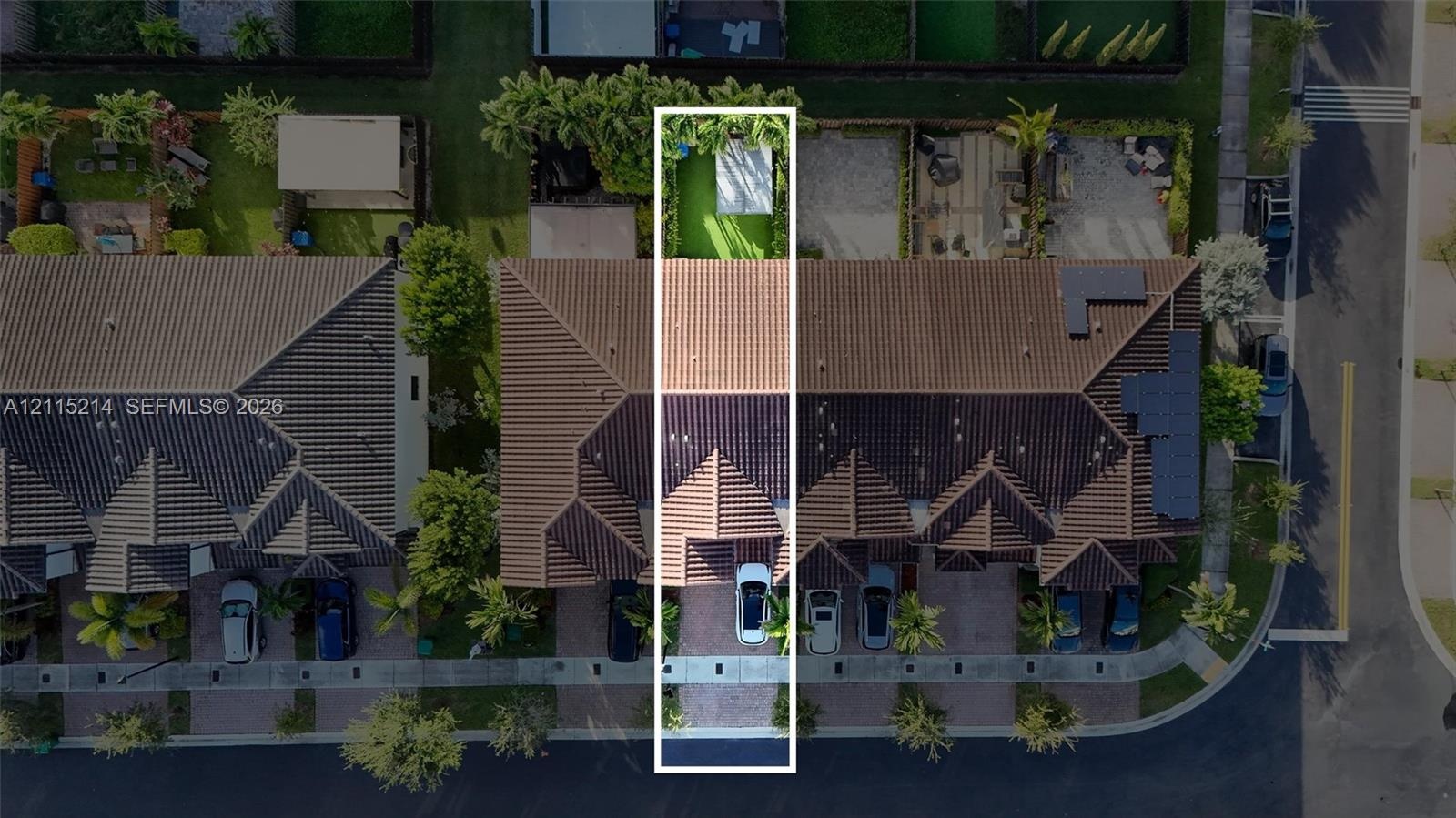 Aerial perspective of property lot featuring a tile roof, paved driveway, and private fenced backyard