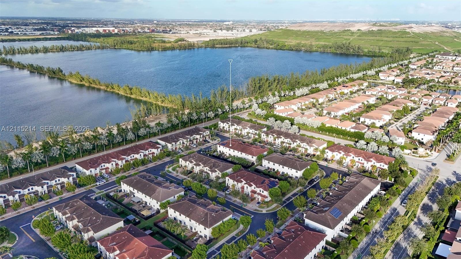 Aerial perspective featuring multi-level residential structures with tile roofing and proximity to a large water basin