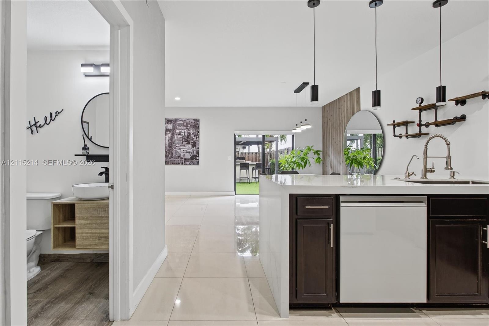 Kitchen island featuring dark cabinetry, quartz countertop, and integrated sink