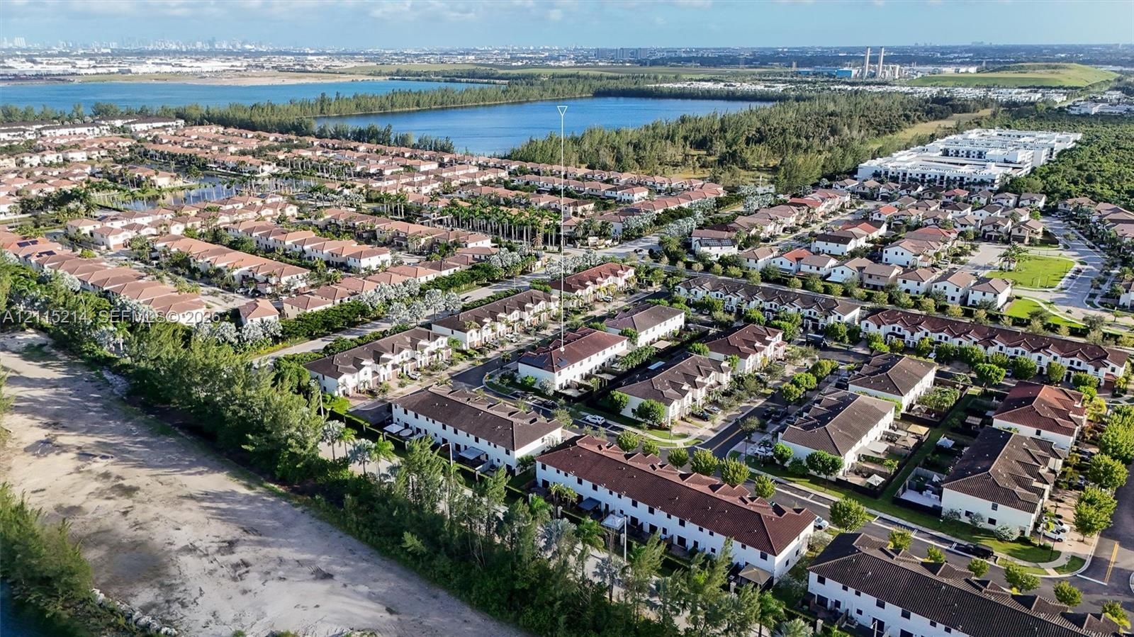 Aerial perspective of a multi-unit residential community featuring terracotta-style tile roofing, stucco facades, structured street layouts, and proxi