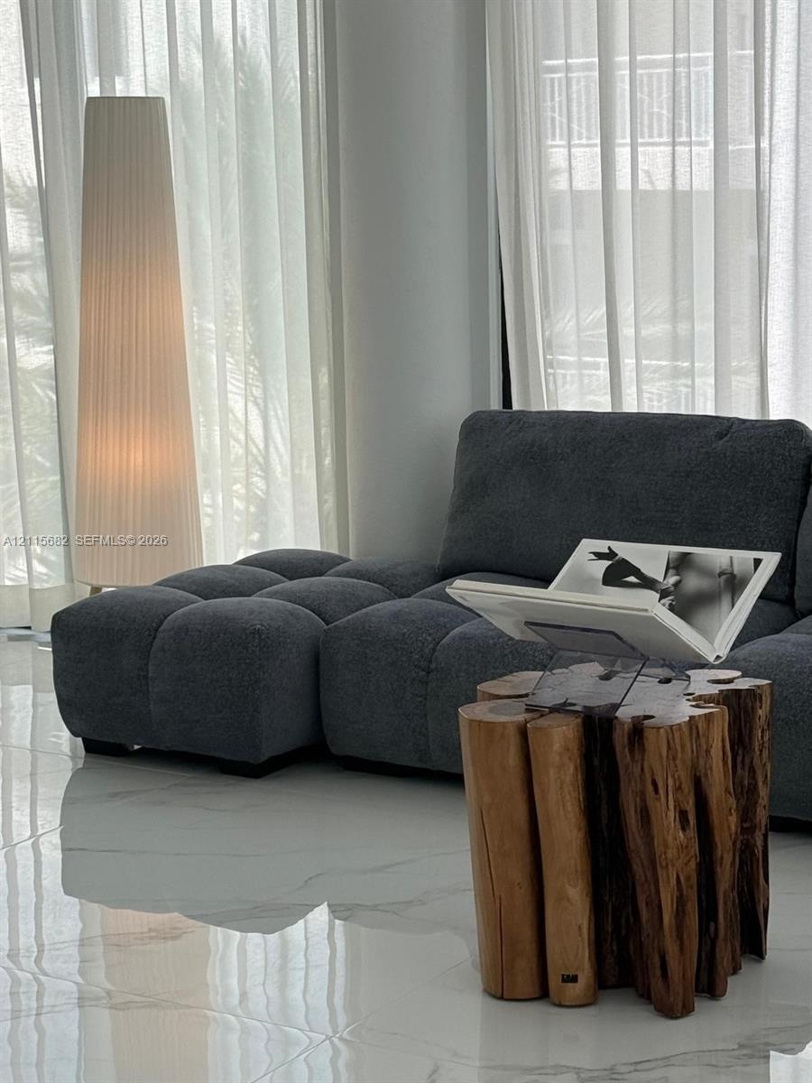 Large-format white polished tile flooring, floor-to-ceiling sheer window treatments, and full-height windows