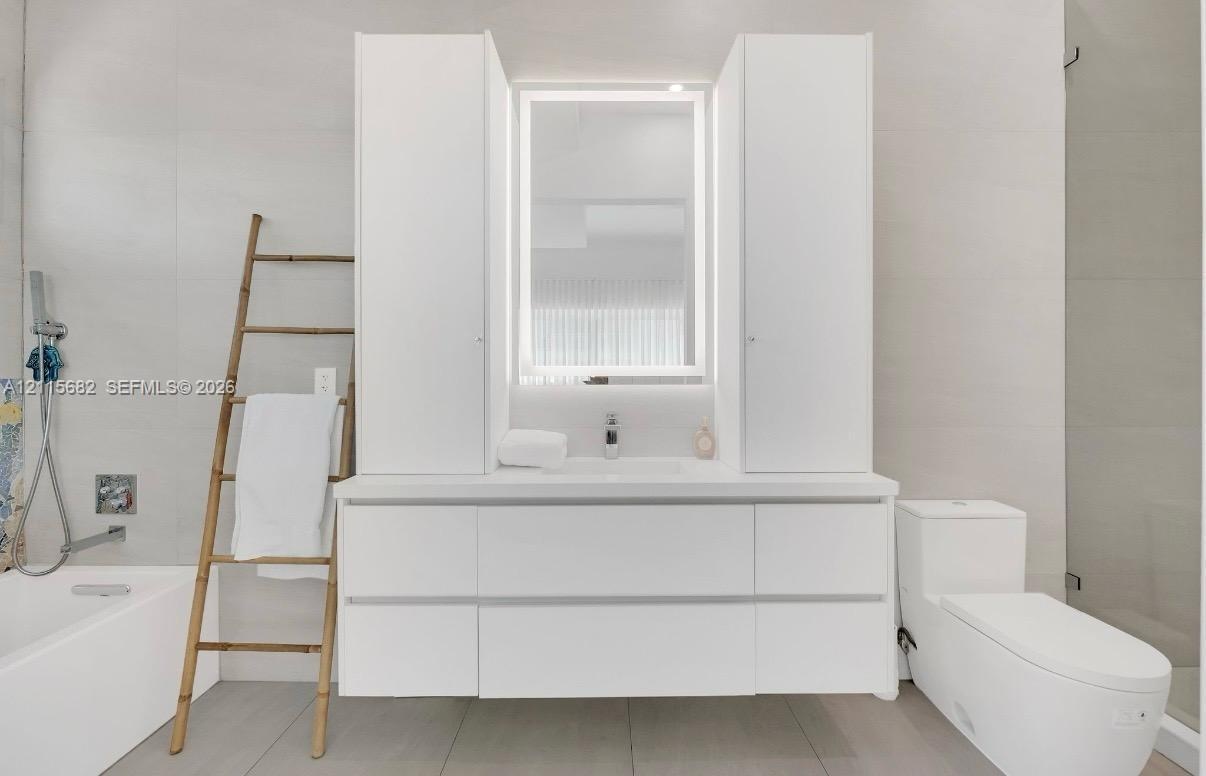 Modern vanity featuring a seamless countertop, integrated cabinetry, and an illuminated mirror