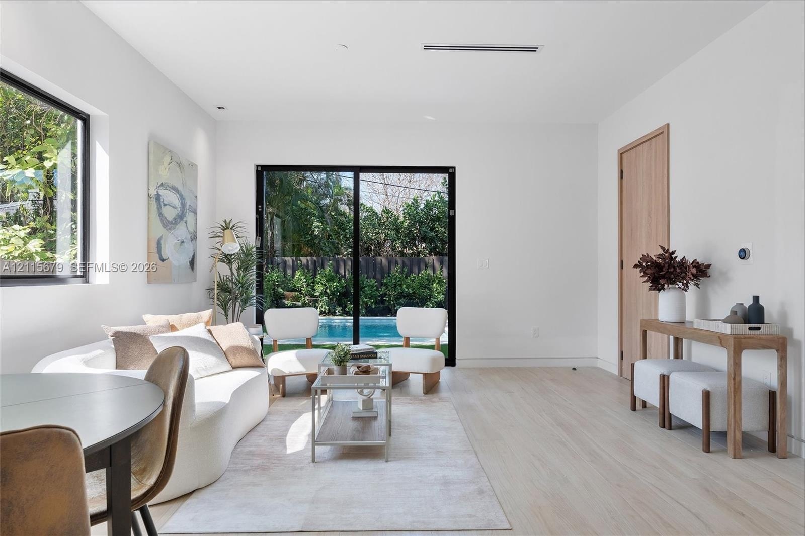 Open-concept interior featuring light wood-finish flooring, sliding glass patio doors, recessed ceiling lighting, and natural wood-tone interior doors